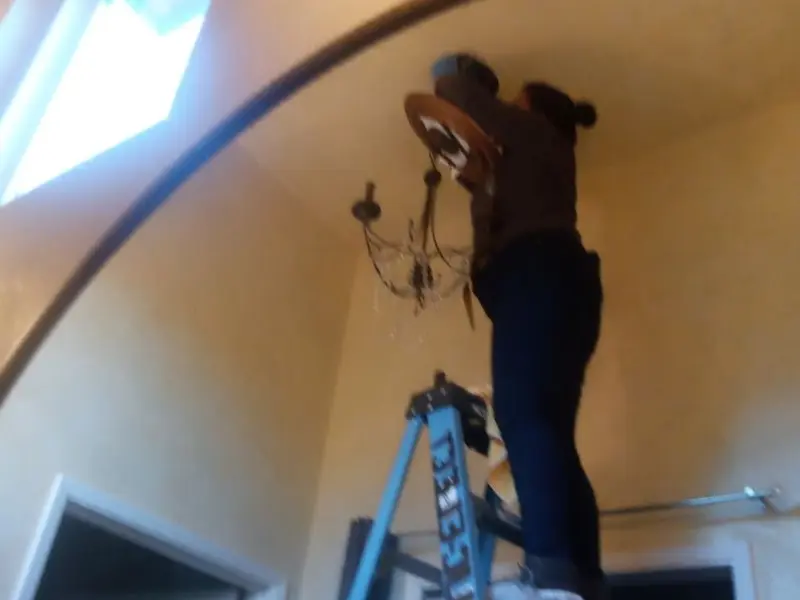 Electrician installing a chandelier in a Bismarck residence